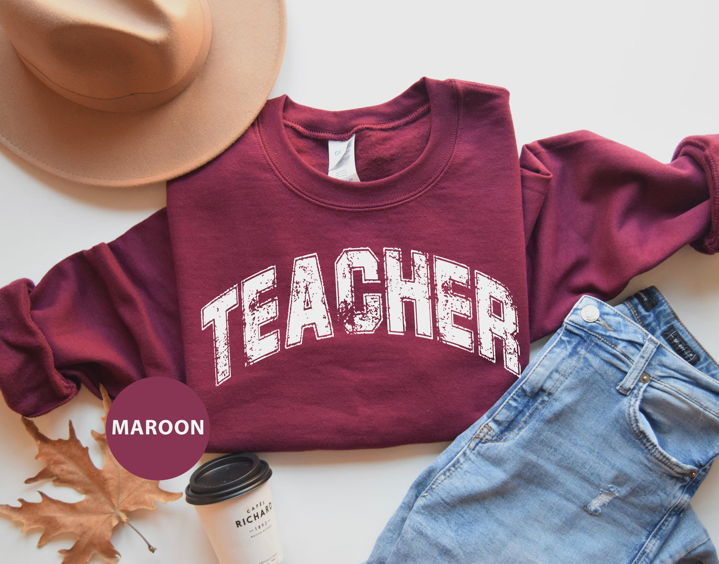 a maroon sweatshirt with the word teacher on it