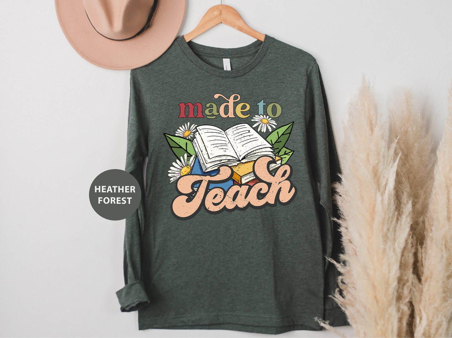 a t - shirt that reads made to teach next to a hat