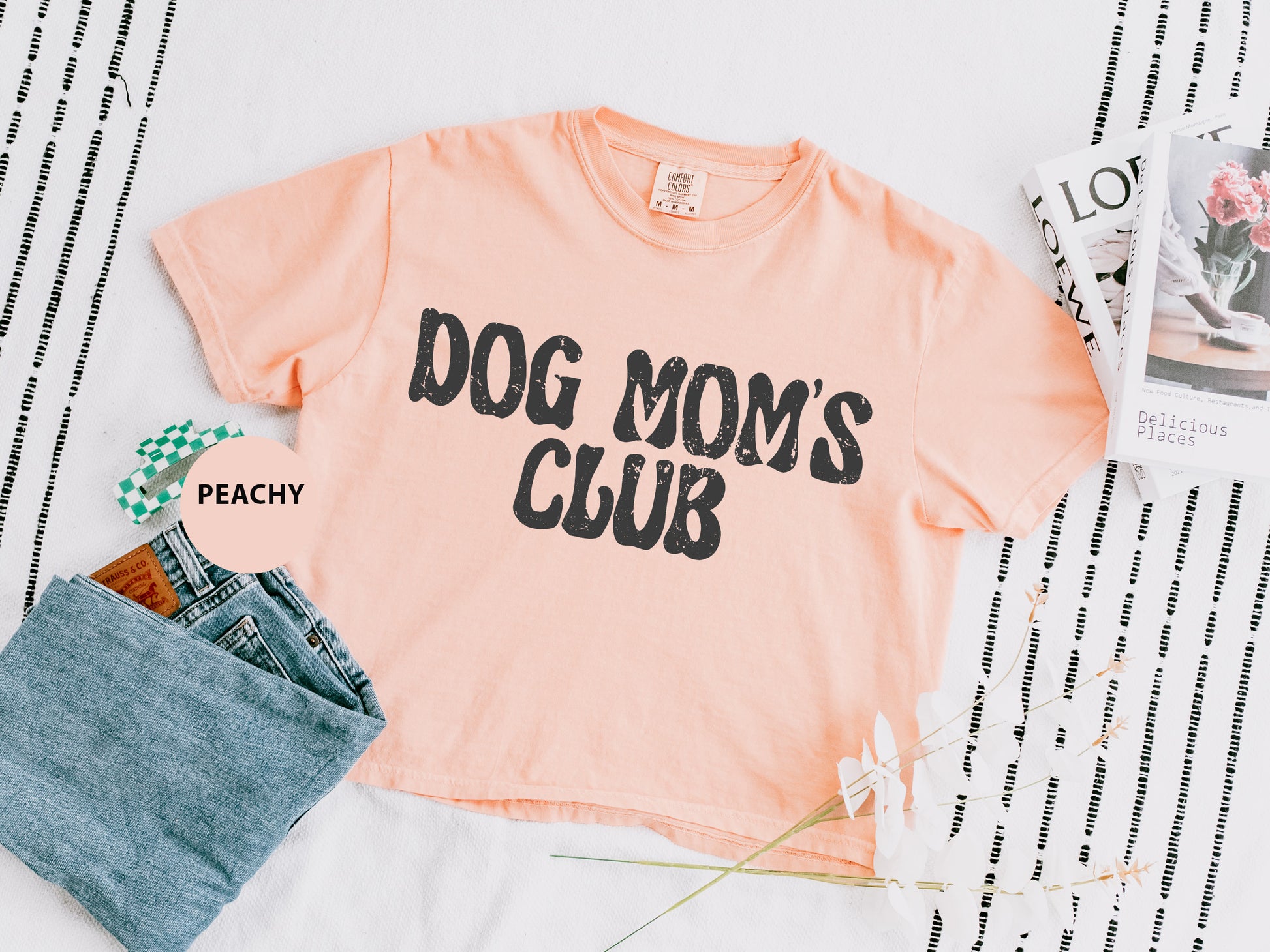 a pink dog mom's club shirt next to a pair of jeans