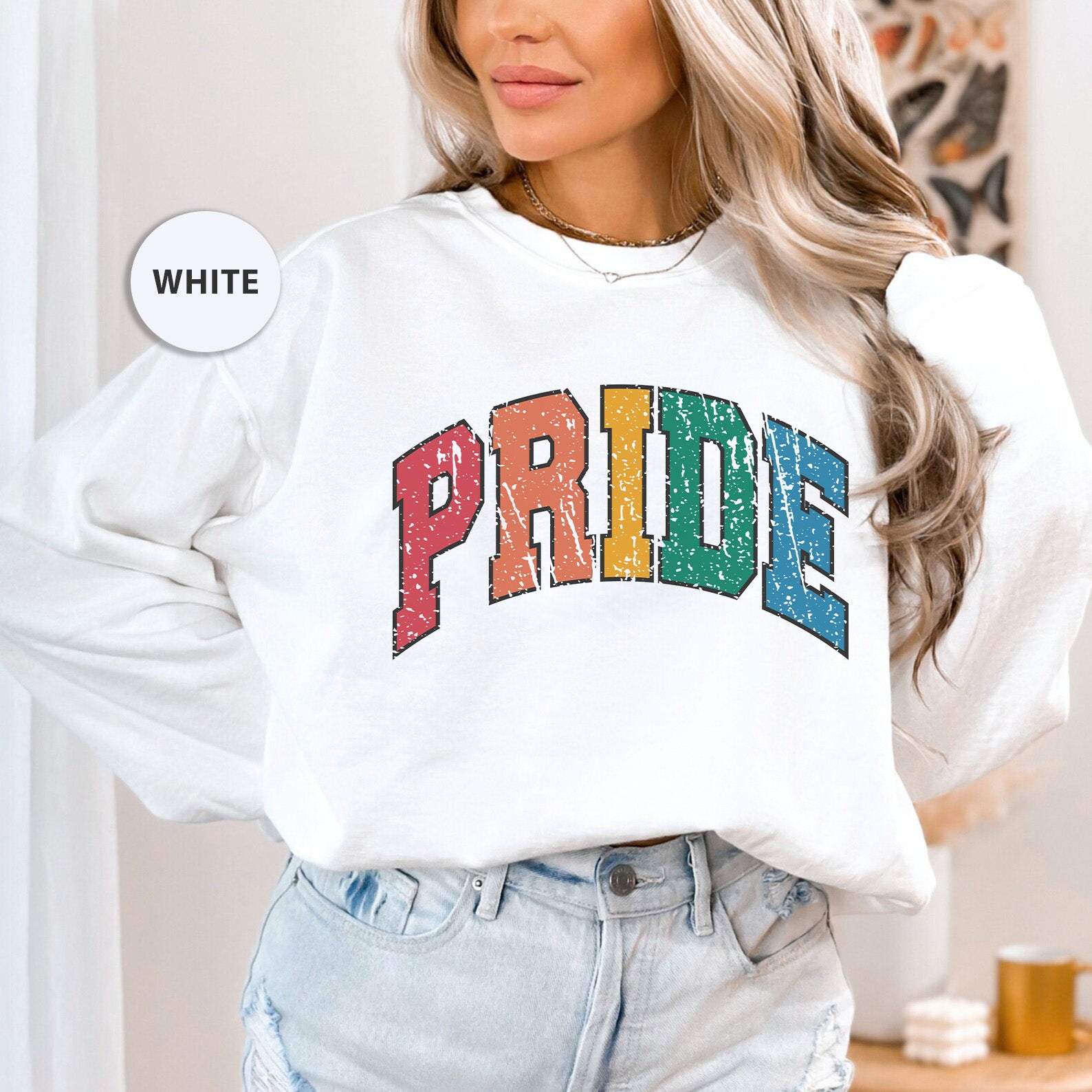 a woman wearing a white sweatshirt with the word pride printed on it