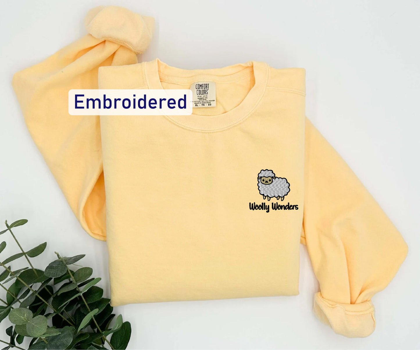 a yellow shirt with an embroidered sheep on it