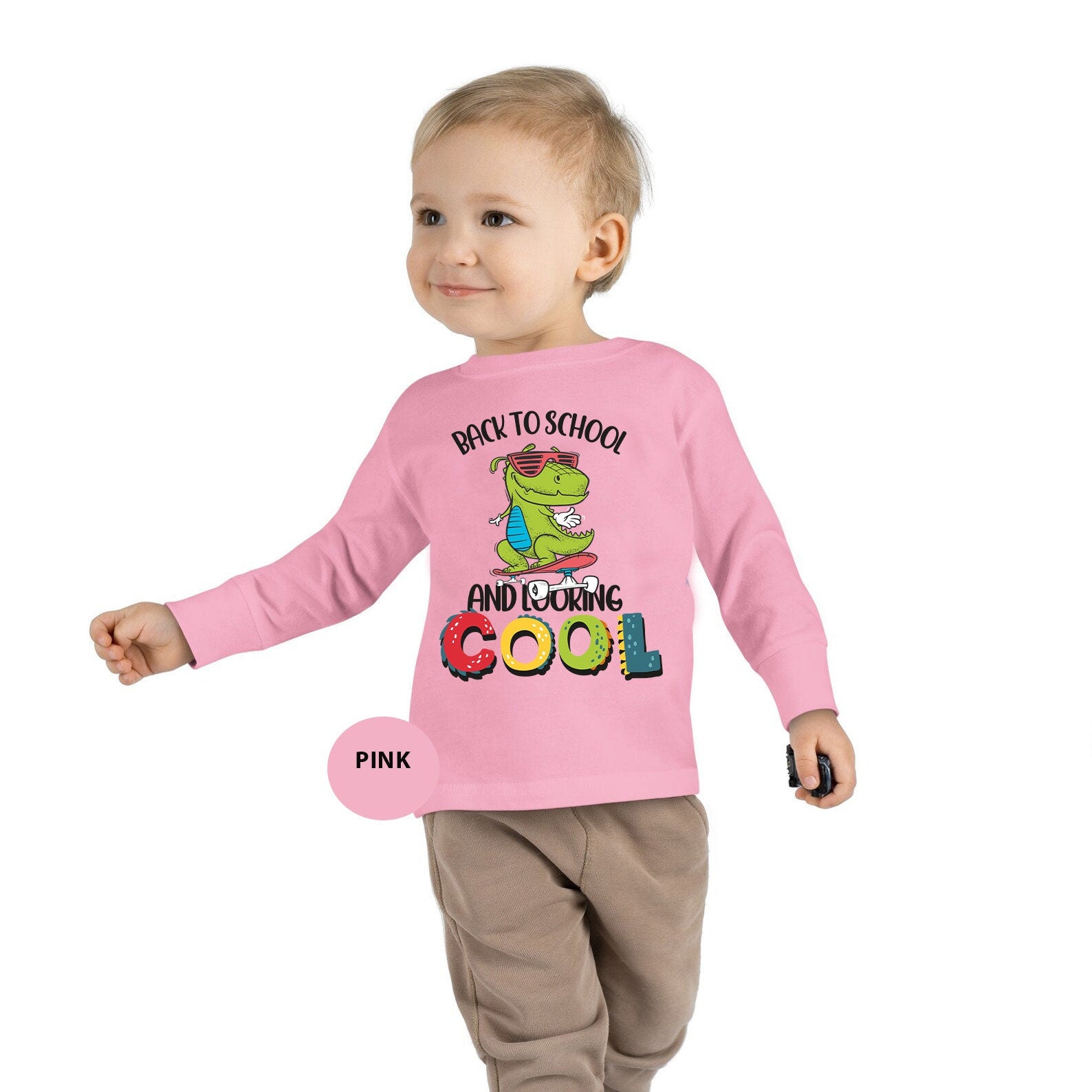 a toddler wearing a pink shirt with a dinosaur on it