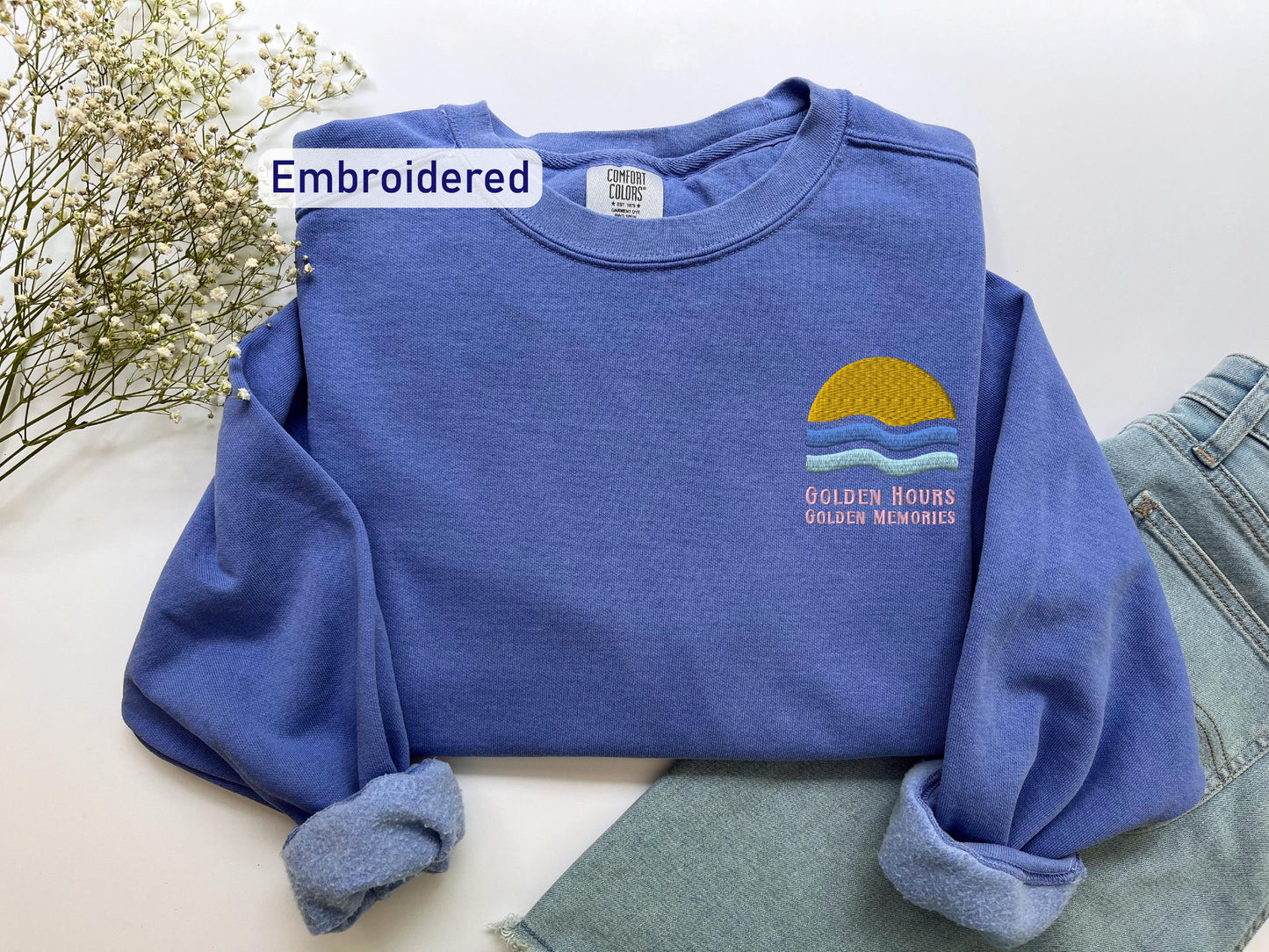 a blue sweatshirt with a yellow sun embroidered on it