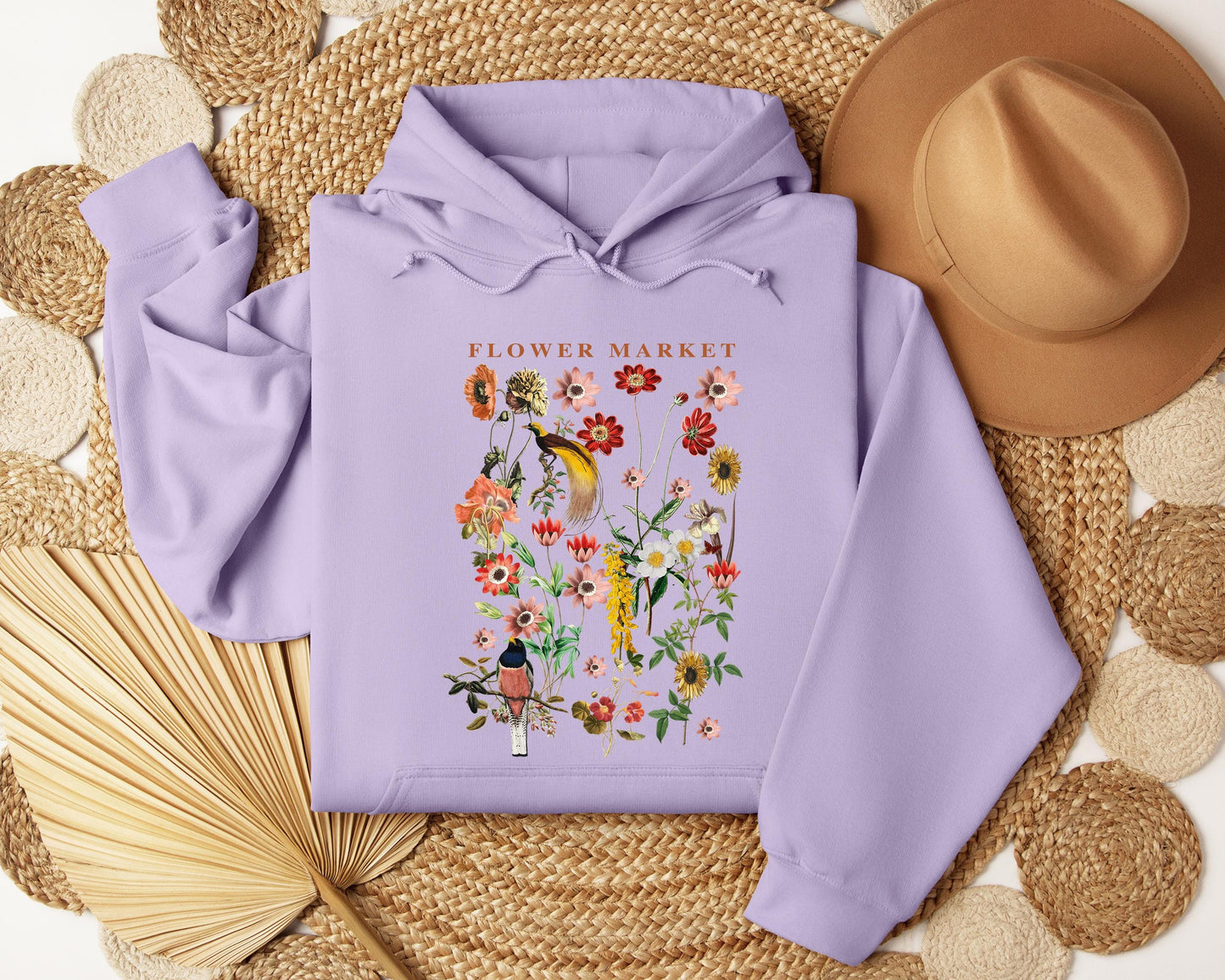 a purple hoodie with flowers on it next to a straw hat