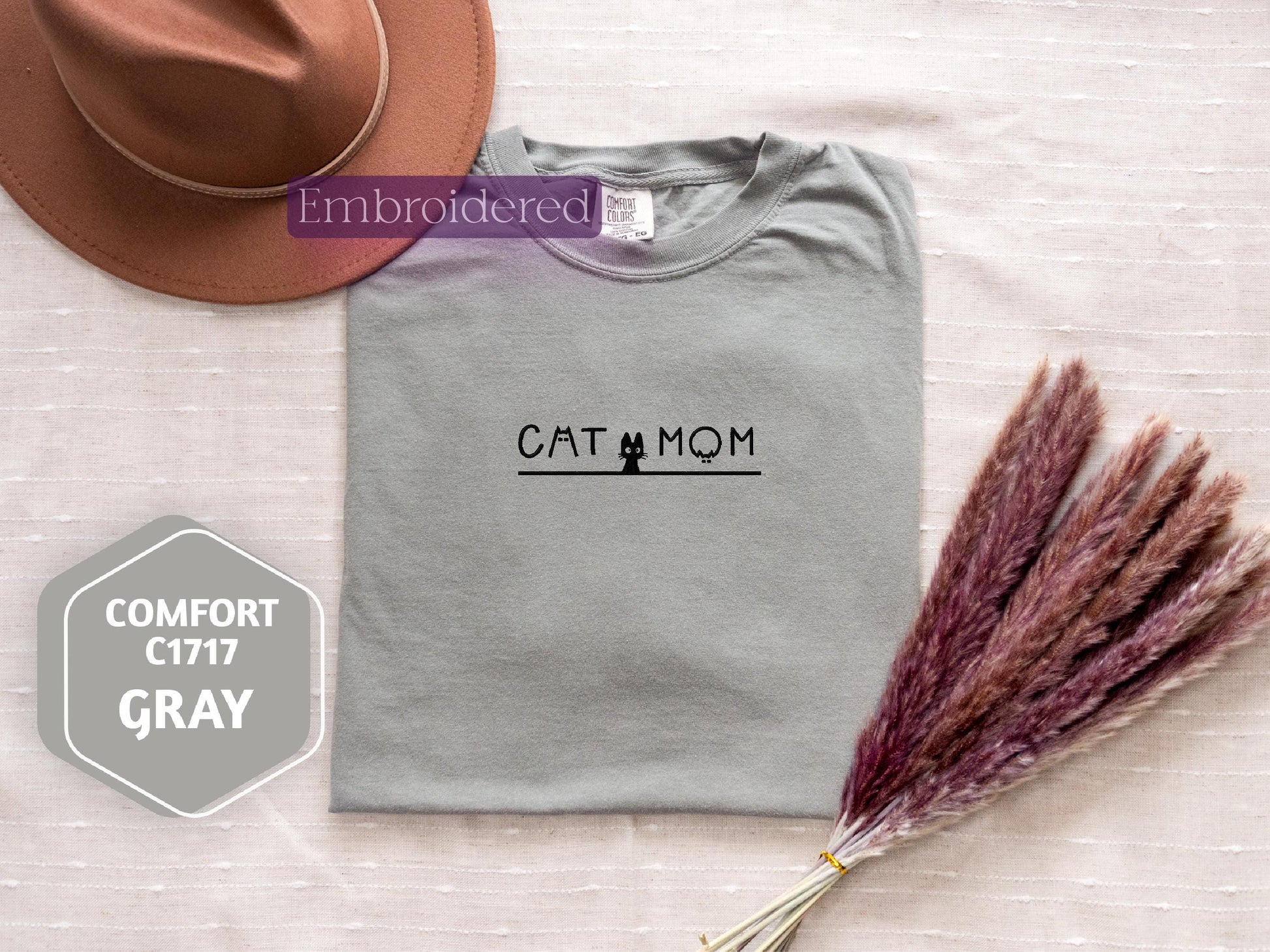 a t - shirt that says cat at mom next to a hat