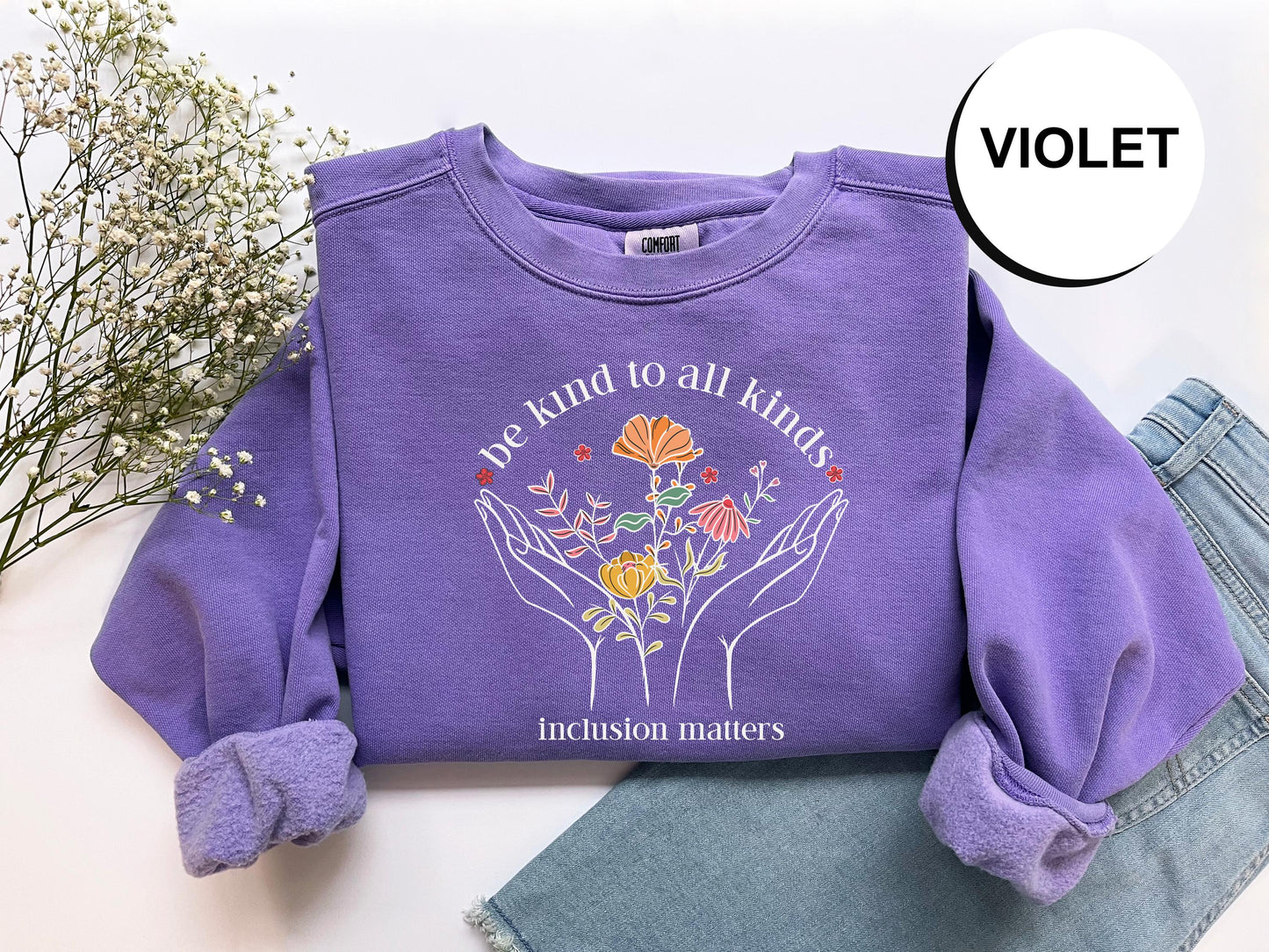 a purple shirt with flowers on it next to a pair of jeans