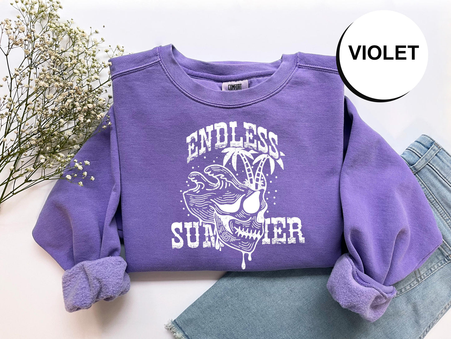 a purple shirt with a skull on it and a pair of jeans next to it