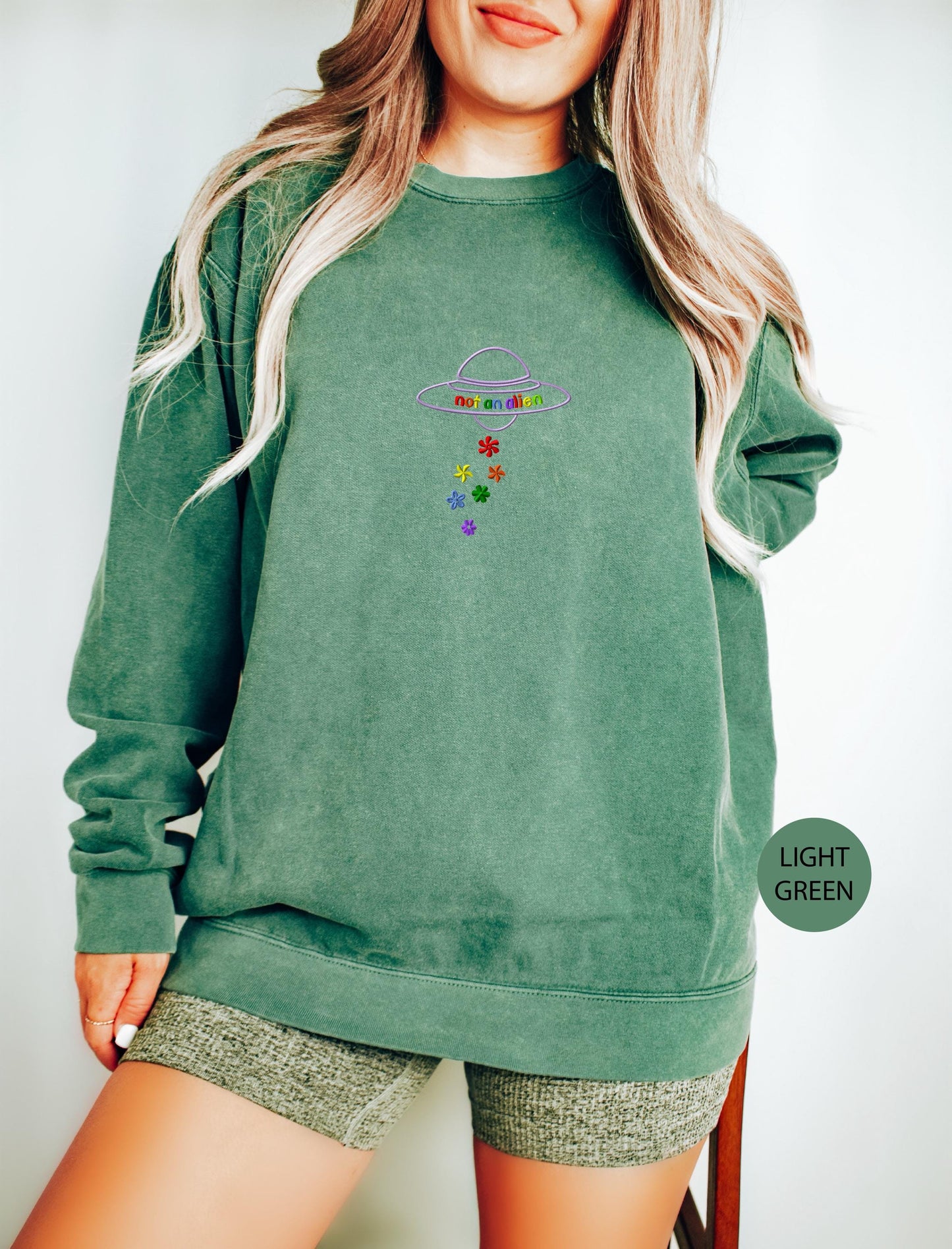 a woman wearing a green sweatshirt and shorts