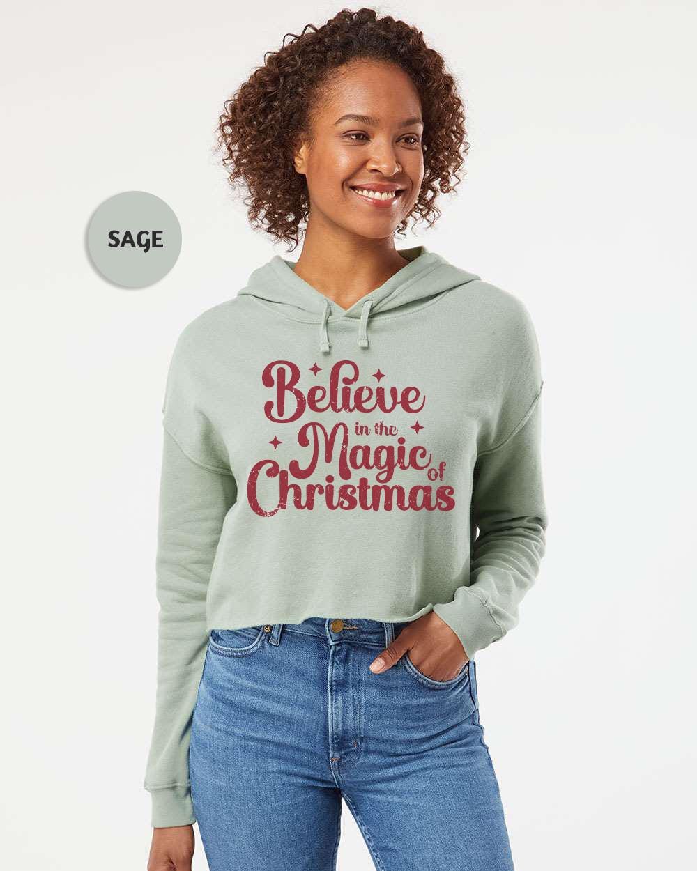 a woman wearing a green hoodie that says believe in the magic of christmas