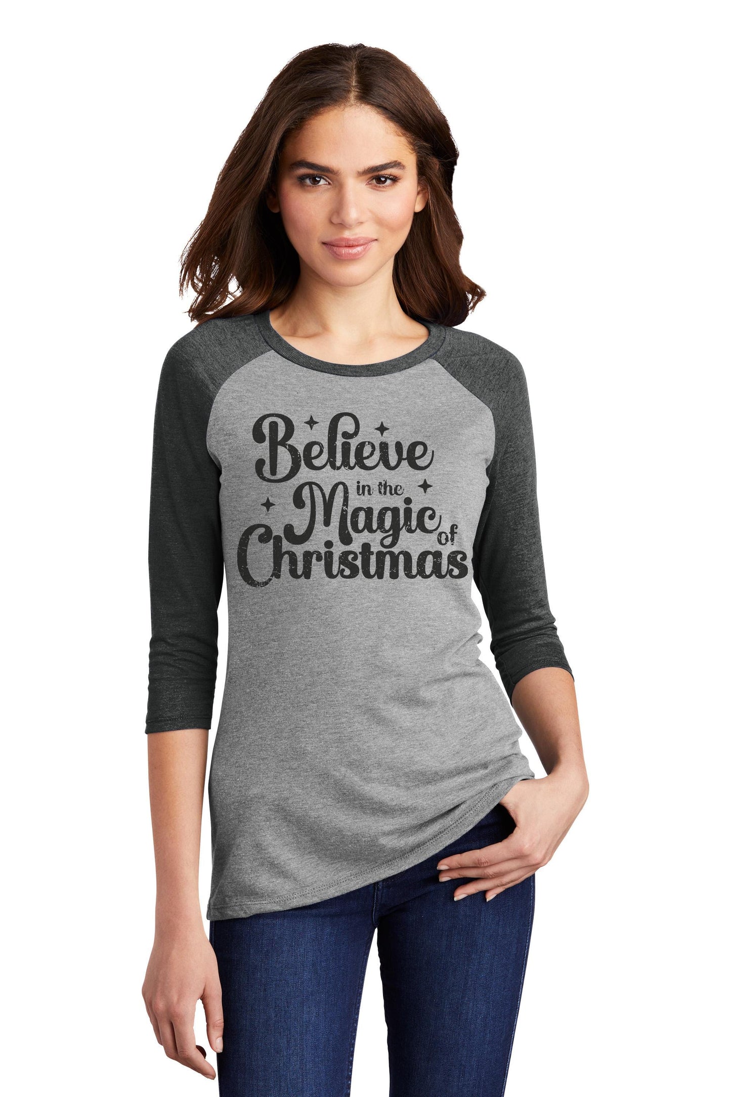 a woman wearing a grey and black shirt that says believe in the magic of christmas