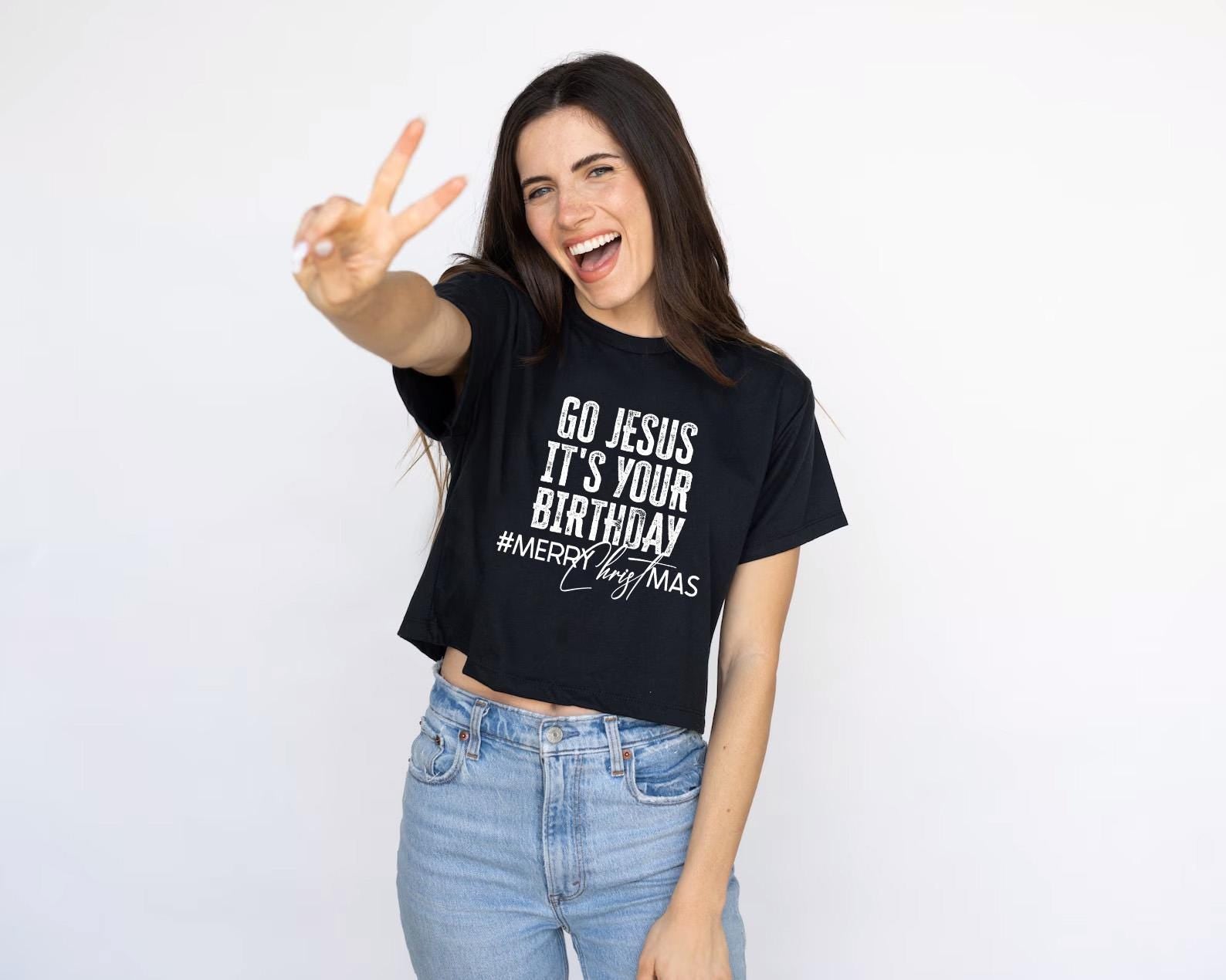 a woman wearing a black t - shirt that says go jesus it's your