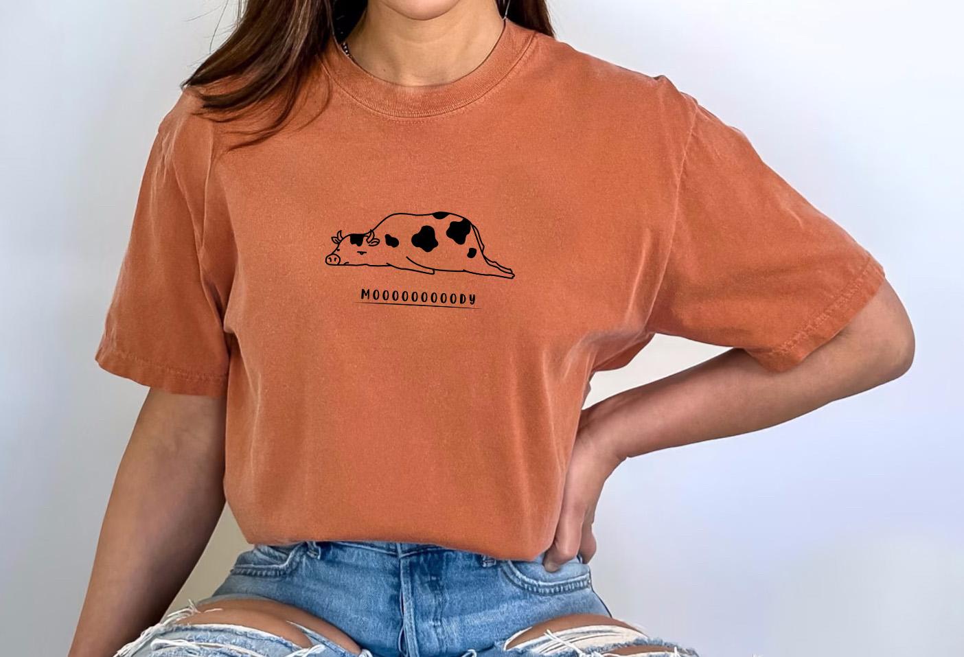a woman wearing a brown shirt with a cow on it