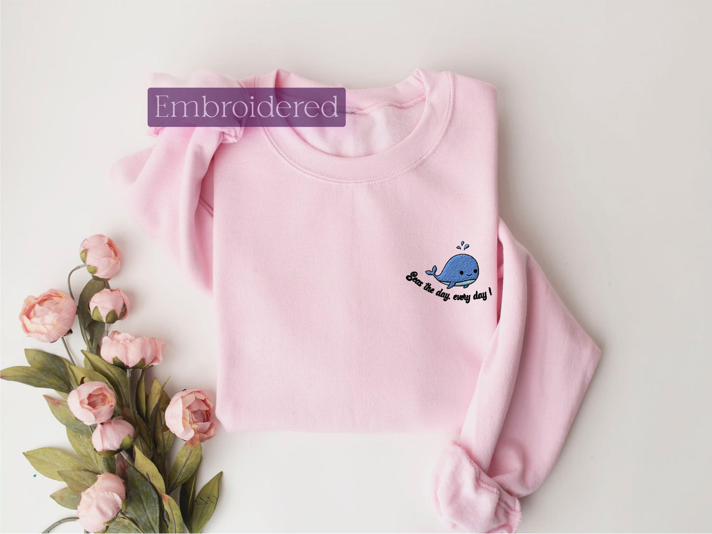 a pink sweater with a blue whale embroidered on it