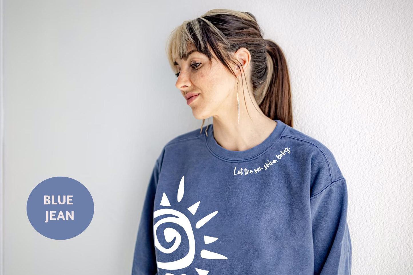 a woman wearing a blue jean sweatshirt standing against a wall