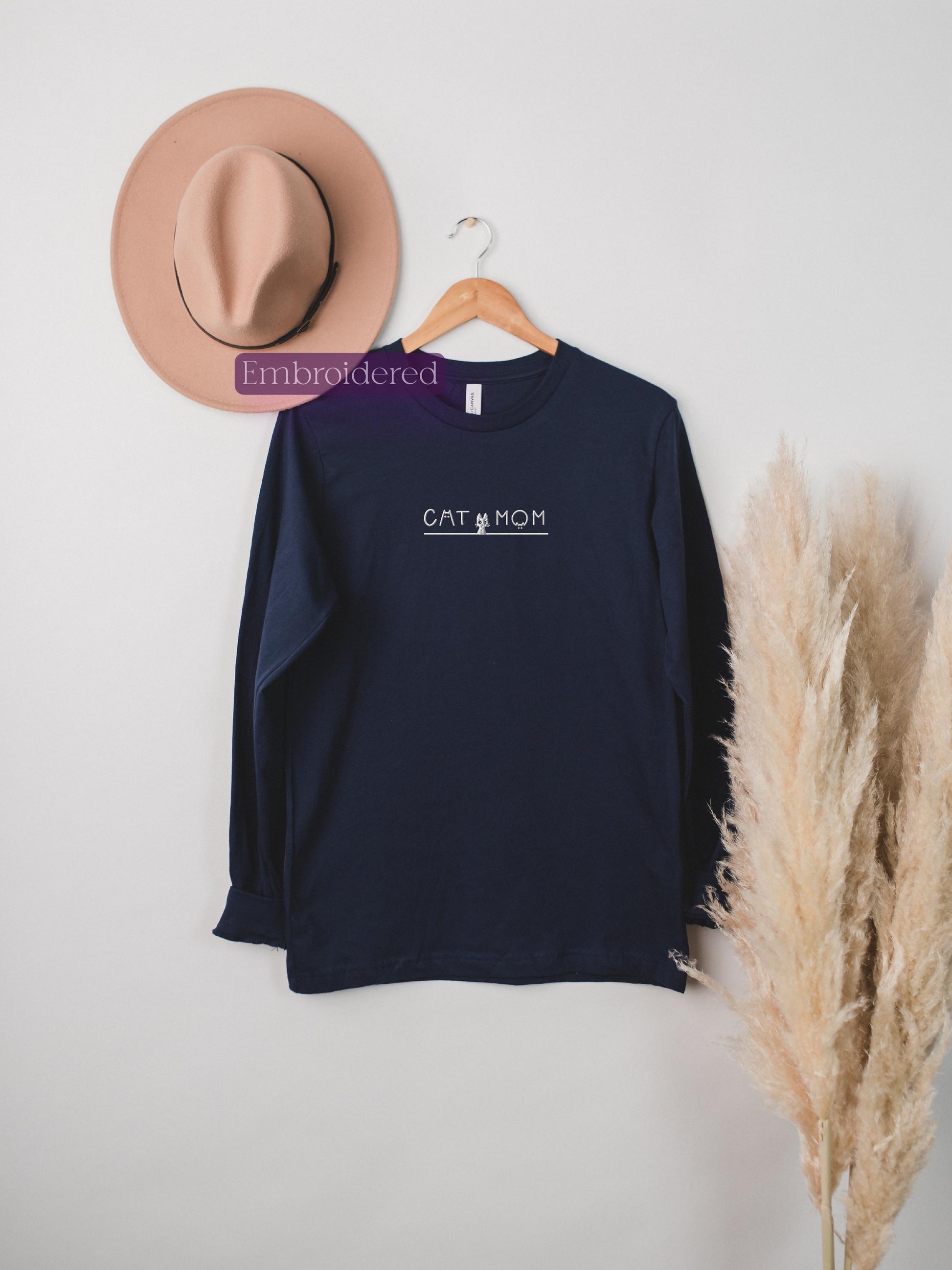 a hat, a t - shirt, and a feather hang on a wall