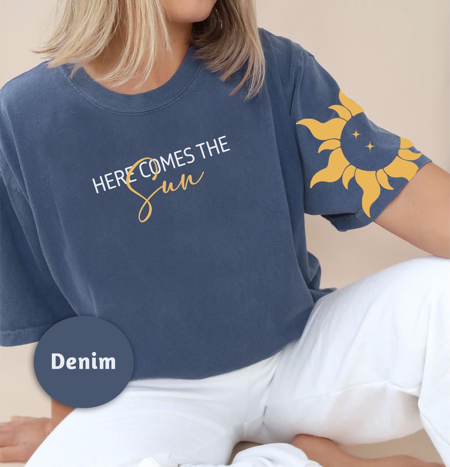 a woman wearing a blue shirt that says here comes the sun