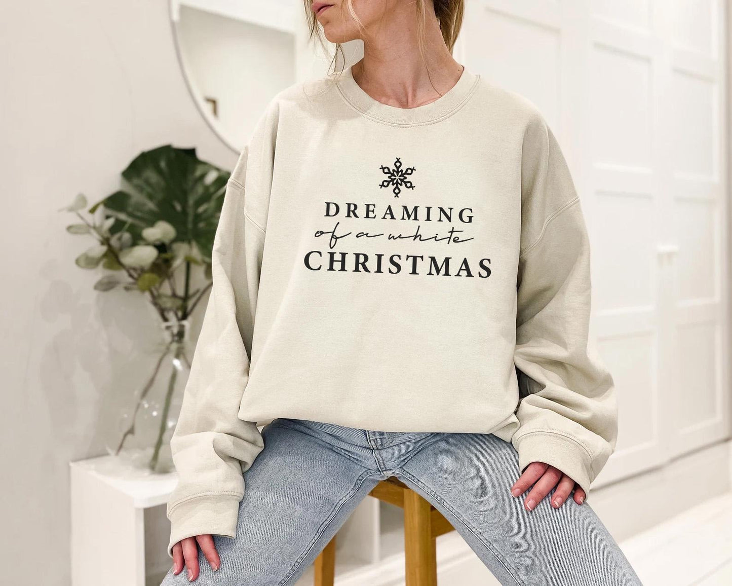 a woman sitting on a stool wearing a sweatshirt