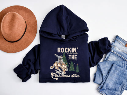 A navy blue hoodie with a graphic design, a brown fedora, a pair of jeans, and a Christmas tree on a white background.