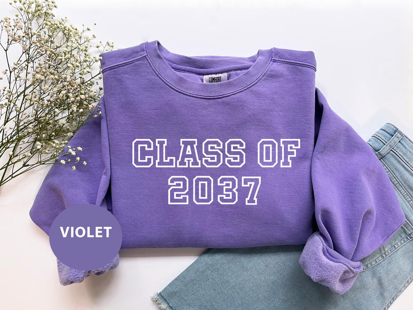 a purple shirt that says class of 2077 next to a pair of jeans