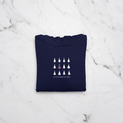 A navy blue hoodie with a white graphic design on the front, featuring a row of white Christmas trees with a single red tree in the center.