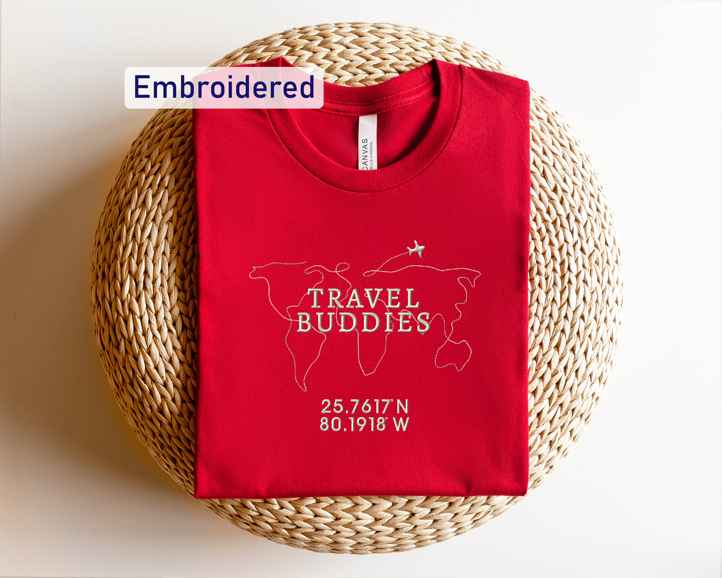 a red travel buddies t - shirt sitting on top of a wicker basket