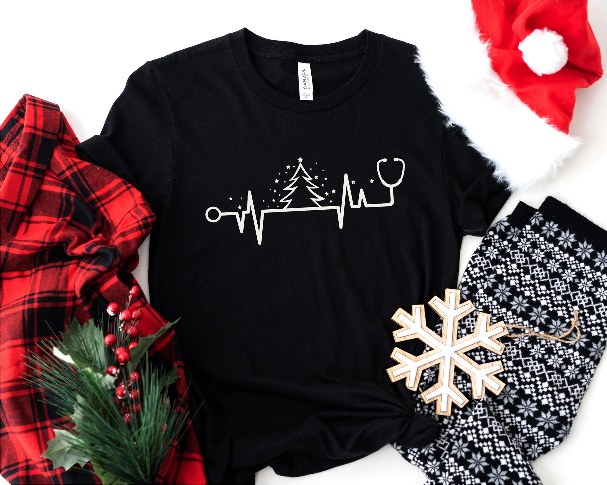 A black t-shirt with a white line design, a red Santa hat, a red and black plaid blanket, a snowflake, and a pair of black and white patterned pajama pants.