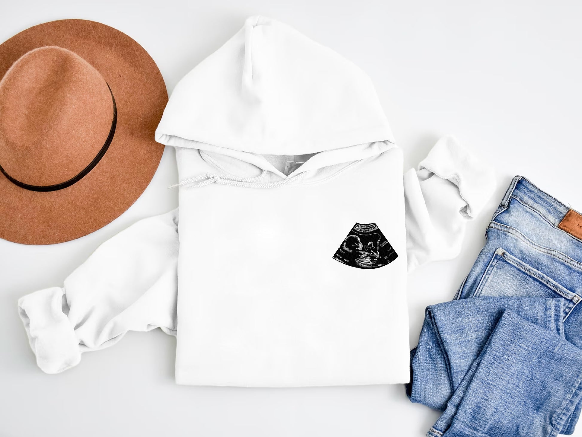 a white hoodie with a hat, jeans, and a pair of jeans