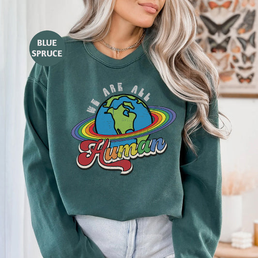 a woman wearing a green sweatshirt with the words we are all human on it