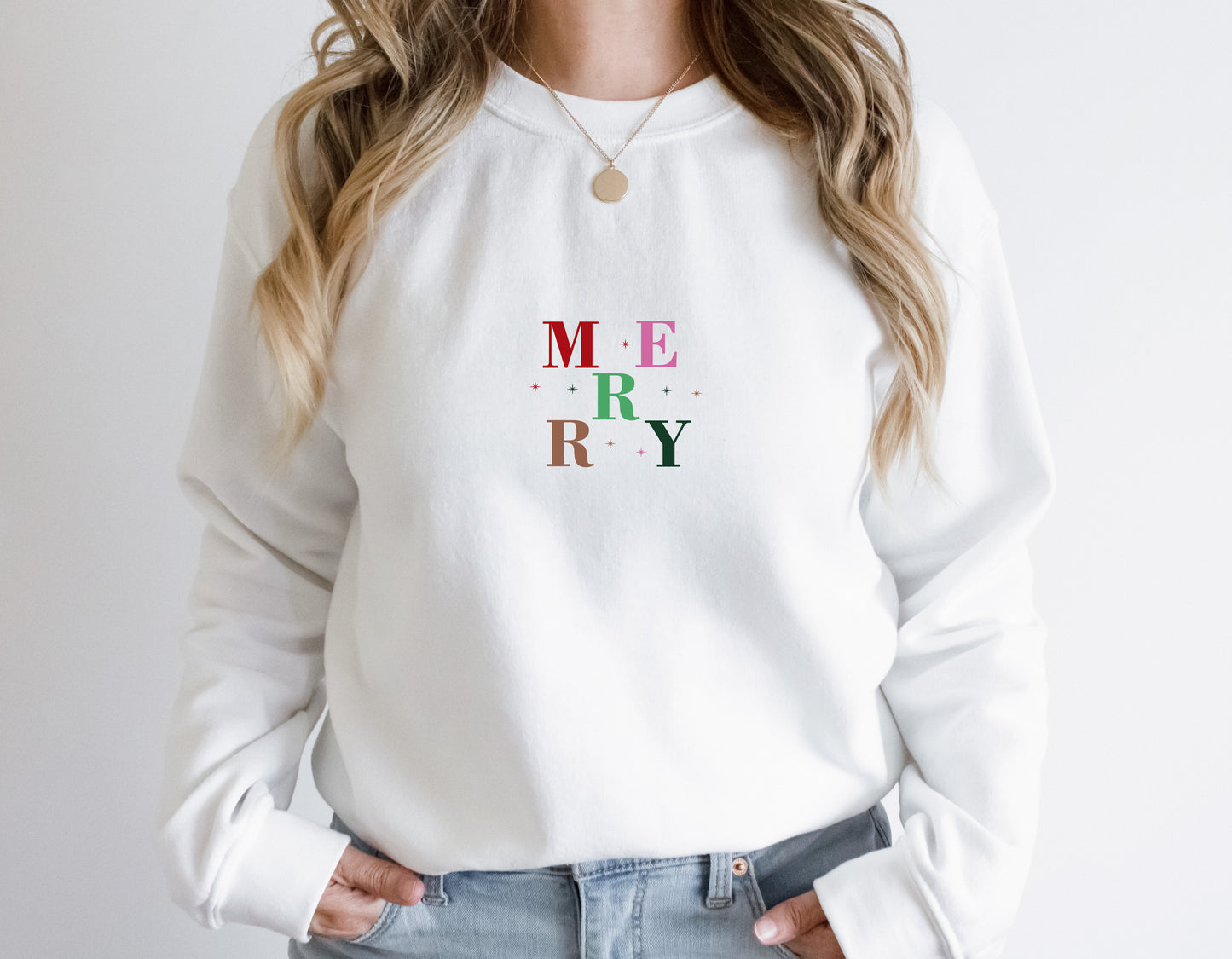 A woman wearing a white sweater with the word "MERRY" printed on it.