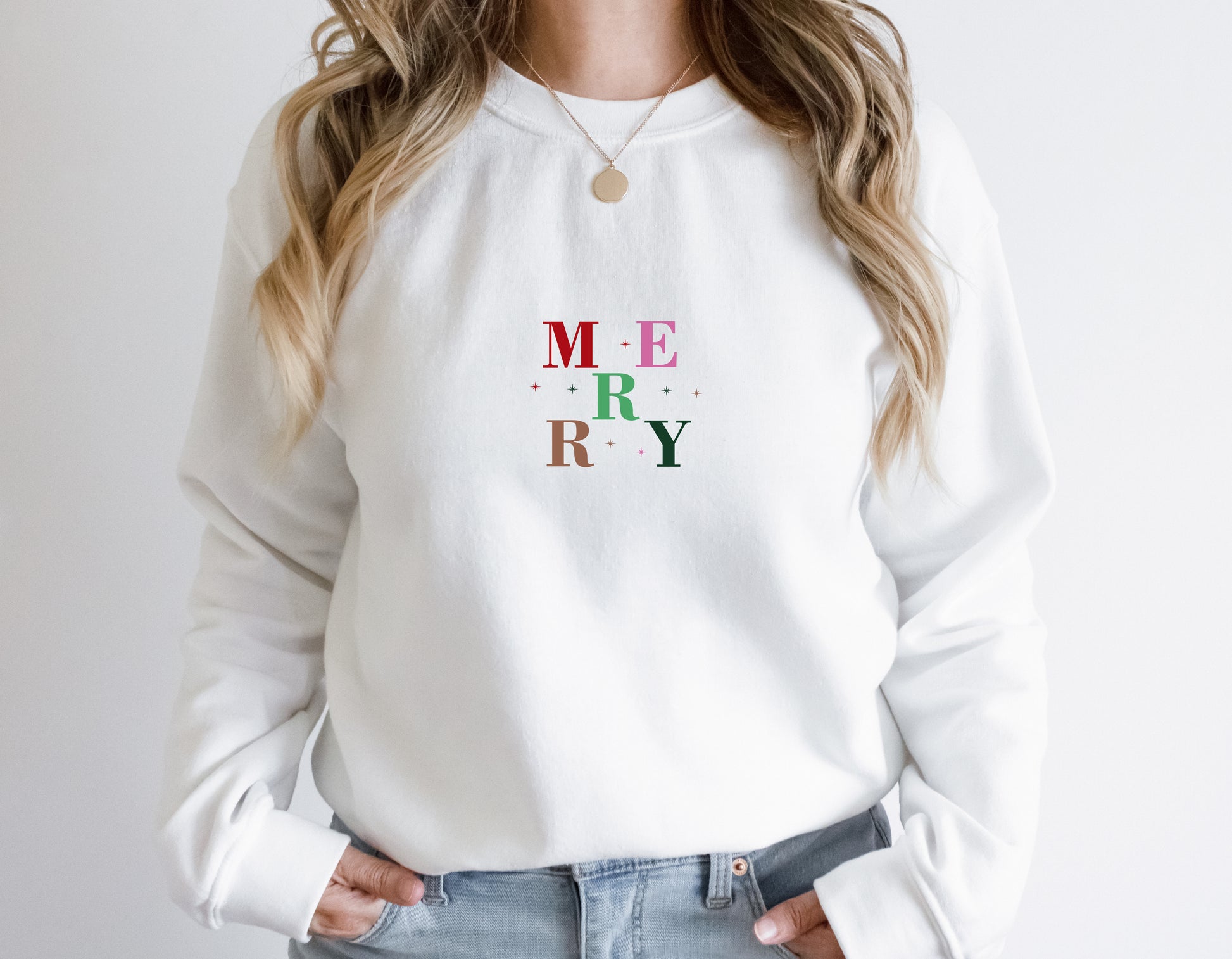 A woman wearing a white sweater with the word "MERRY" printed on it.