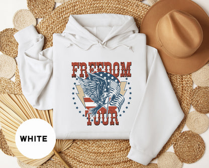 a white hoodie with a graphic design of an eagle and the words "FREEDOM TOUR" printed on it, along with a brown hat and a fan.
