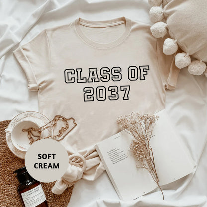 a t - shirt that says class of 2077 next to a bottle of cream