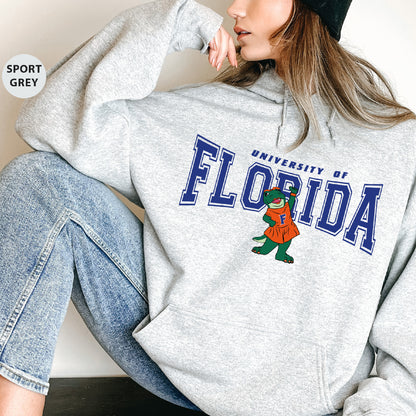 a woman sitting on the ground wearing a sweatshirt