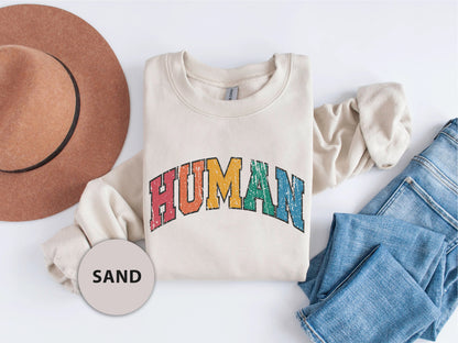 a white shirt with the word human on it next to jeans and a hat