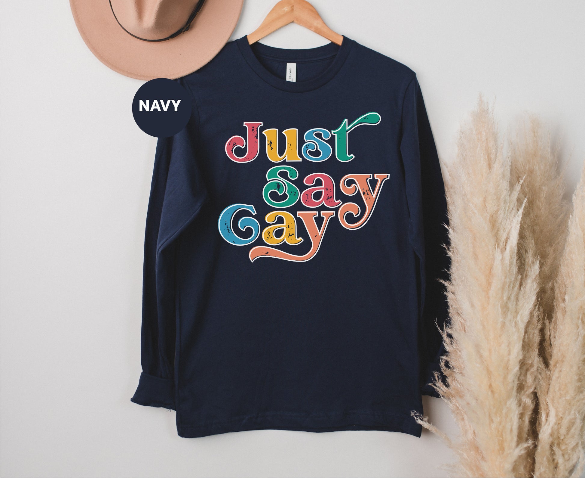 a t - shirt that says just sasy gay on it next to a hat