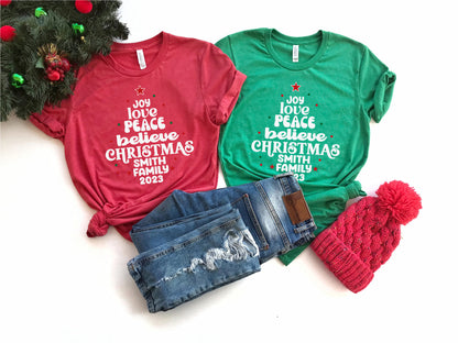 a collection of Christmas-themed items, including two t-shirts with holiday-themed text, a pair of jeans, and a red knit hat.