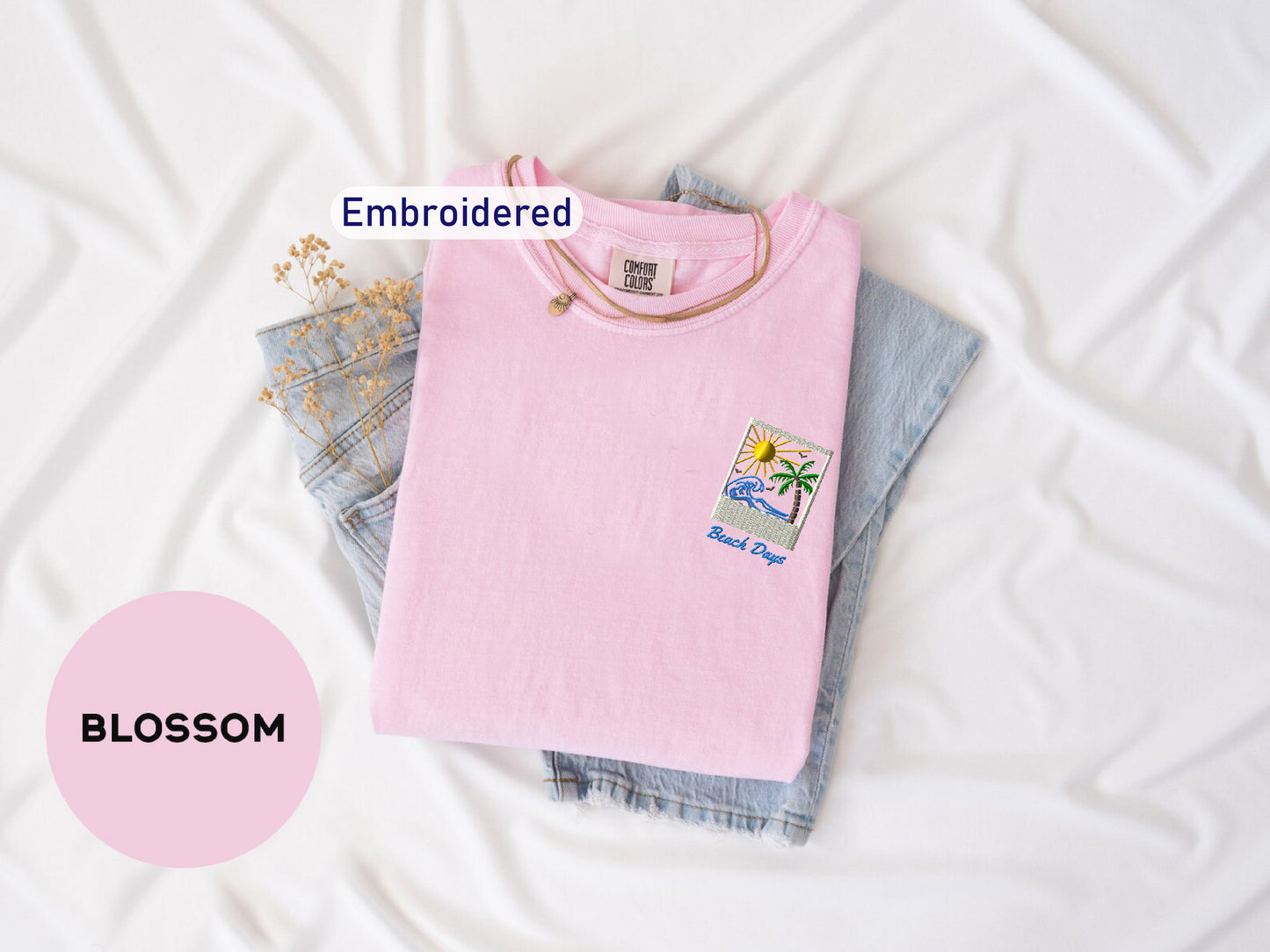 a pink t-shirt with a beach-themed patch, a pair of denim jeans, and a white sheet with the word "BLOSOM" written on it.
