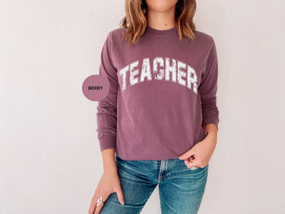 a woman wearing a sweatshirt with the word teacher on it