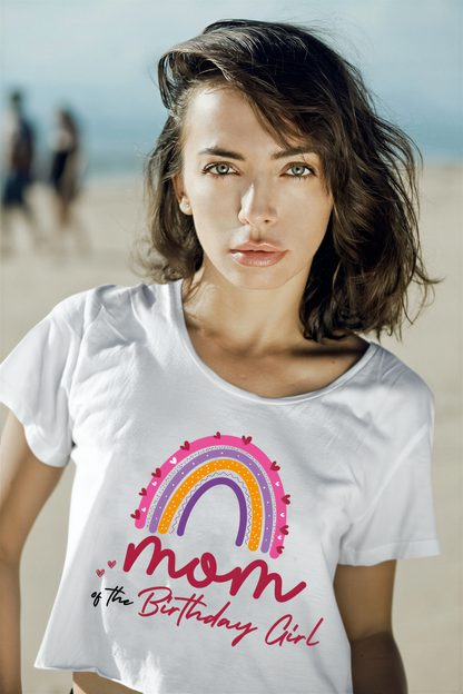 A woman wearing a white t-shirt with a colorful graphic design and text, standing on a beach.