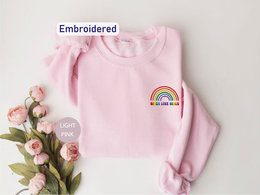 a pink sweater with a rainbow embroidered on it