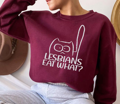 a woman sitting on a bed wearing a sweatshirt that says lesbians eat what?