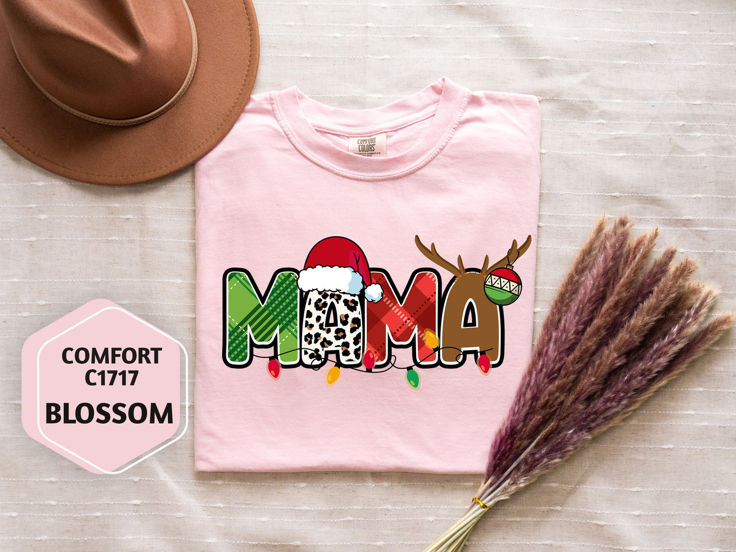 a pink t-shirt with a Christmas-themed design, a brown hat, and some decorative reindeer antlers.