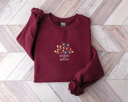 A burgundy sweatshirt with a Christmas-themed design and the text "MERRY ON BRIGHT" printed on it.