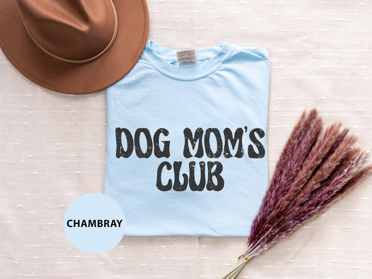 a dog mom's club t - shirt with a hat next to it