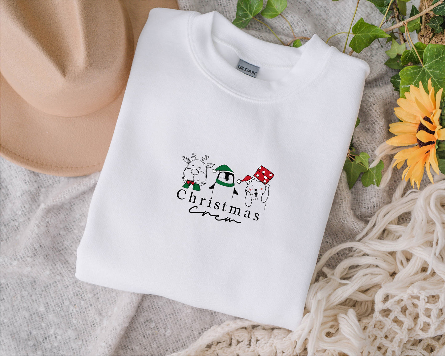 A white t-shirt with a Christmas-themed graphic design, including a reindeer, penguin, and snowman, along with the text "Christmas" printed on it.