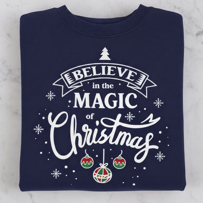 A navy blue sweatshirt with a white and red Christmas-themed design and text that reads "Believe in the Magic of Christmas".