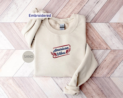 a cream-colored sweater with a red and blue embroidered design on the front, placed on a wooden surface.