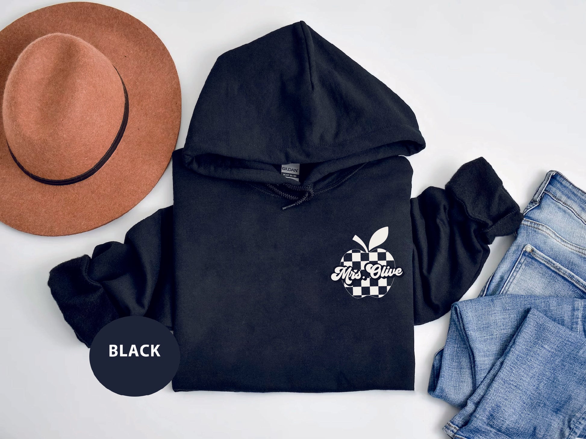 a black hoodie with an apple on it next to jeans and a hat