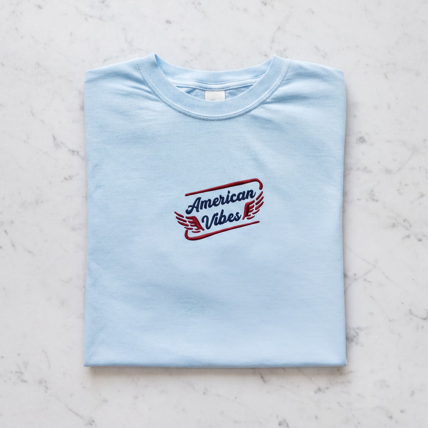 A light blue t-shirt with the text "American Vibes" printed on it.