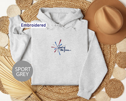 a grey hoodie with a colorful design, a brown hat, and some woven straw items, all arranged on a woven mat.